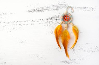 Parlak çok renkli Rüya yakalayıcı turuncu bir barış işareti ve beyaz eski püskü ahşap zemin üzerinde turuncu sarı tüyleri ile. Metin için yer kopyalayın.