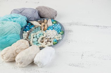 Konu ve boncuk ve kabukları üzerinde eski püskü Beyaz ahşap arka plan gri plaka örgü. Metin için yer kopyalayın.