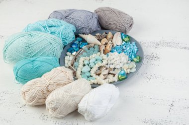 Konu ve boncuk ve kabukları üzerinde eski püskü Beyaz ahşap arka plan gri plaka örgü. Metin için yer kopyalayın.