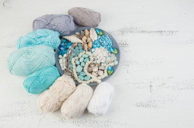 Konu ve boncuk ve kabukları üzerinde eski püskü Beyaz ahşap arka plan gri plaka örgü. Metin için yer kopyalayın.