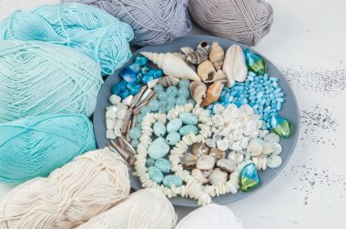 Konu ve boncuk ve kabukları üzerinde eski püskü Beyaz ahşap arka plan gri plaka örgü. Metin için yer kopyalayın.