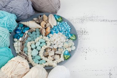 Konu ve boncuk ve kabukları üzerinde eski püskü Beyaz ahşap arka plan gri plaka örgü. Metin için yer kopyalayın.