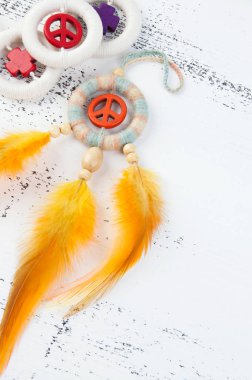 Parlak çok renkli Rüya yakalayıcı turuncu bir barış işareti ve beyaz eski püskü ahşap zemin üzerinde turuncu sarı tüyleri ile. Metin için yer kopyalayın.