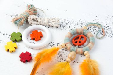 Rüya yakalayıcı turuncu barış işareti ile parlak çok renkli ve beyaz eski püskü ahşap zemin üzerinde turuncu sarı tüyler yakın çekim. Metin için yer kopyalayın.