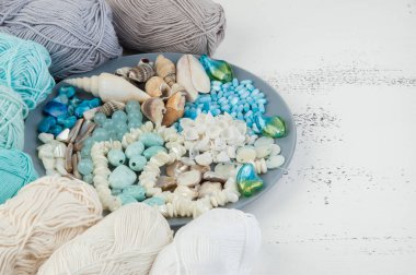 Konu ve boncuk ve kabukları üzerinde eski püskü Beyaz ahşap arka plan gri plaka örgü. Metin için yer kopyalayın.