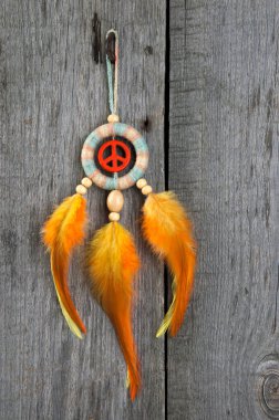 Parlak çok renkli Rüya yakalayıcı turuncu bir barış işareti ve eski gri ahşap arka plan üzerinde turuncu sarı tüyleri ile. Metin için yer kopyalayın.