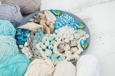 Konu ve boncuk ve kabukları üzerinde eski püskü Beyaz ahşap arka plan gri plaka örgü. Metin için yer kopyalayın.