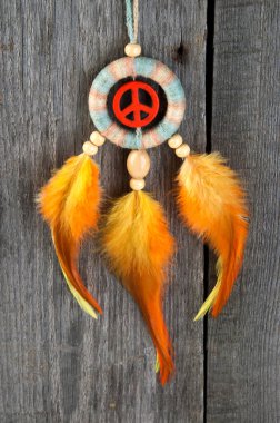 Parlak multi dreamcatcher turuncu bir barış işareti ve eski gri ahşap arka plan turuncu sarı tüyler ile renkli. Metin için yer kopyalayın.