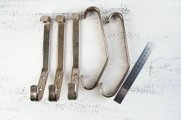 Five vintage metal hooks hangers on shabby white wooden background. Copy space for text.