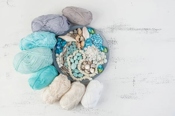 Konu ve boncuk ve kabukları üzerinde eski püskü Beyaz ahşap arka plan gri plaka örgü. Metin için yer kopyalayın.