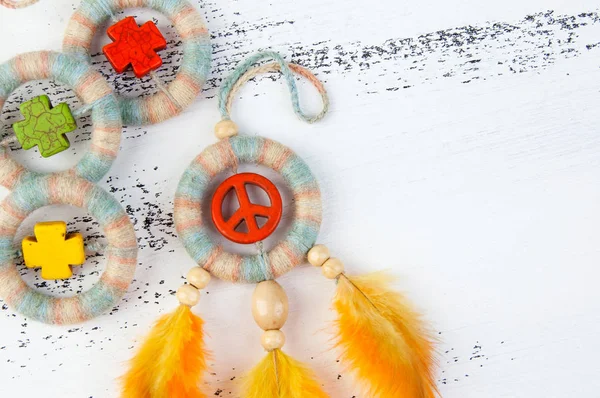 Rüya yakalayıcı turuncu barış işareti ile parlak çok renkli ve beyaz eski püskü ahşap zemin üzerinde turuncu sarı tüyler yakın çekim. Metin için yer kopyalayın.