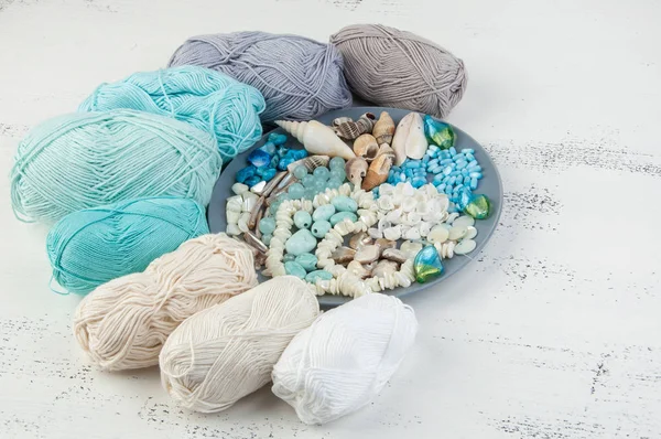 Konu ve boncuk ve kabukları üzerinde eski püskü Beyaz ahşap arka plan gri plaka örgü. Metin için yer kopyalayın.