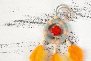 Parlak çok renkli Rüya yakalayıcı turuncu bir haç ve beyaz eski püskü ahşap zemin üzerinde turuncu sarı tüyleri ile. Metin için yer kopyalayın.