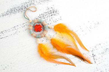 Parlak çok renkli Rüya yakalayıcı turuncu bir haç ve beyaz eski püskü ahşap zemin üzerinde turuncu sarı tüyleri ile. Metin için yer kopyalayın.