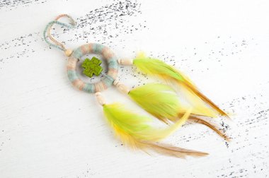 Parlak çok renkli Rüya yakalayıcı yeşil haç ve beyaz eski püskü ahşap zemin üzerinde turuncu sarı tüyleri ile. Metin için yer kopyalayın.