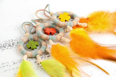 Parlak çok rüya yakalayıcı haçlar ve turuncu sarı tüyleri beyaz eski püskü ahşap arka plan üzerinde renkli. Metin için yer kopyalayın.