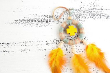 Parlak çok renkli Rüya yakalayıcı sarı çapraz ve beyaz eski püskü ahşap zemin üzerinde turuncu sarı tüyleri ile. Metin için yer kopyalayın.