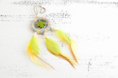 Parlak çok renkli Rüya yakalayıcı yeşil haç ve beyaz eski püskü ahşap zemin üzerinde turuncu sarı tüyleri ile. Metin için yer kopyalayın.