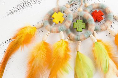 Parlak çok rüya yakalayıcı haçlar ve turuncu sarı tüyleri beyaz eski püskü ahşap arka plan üzerinde renkli. Metin için yer kopyalayın.