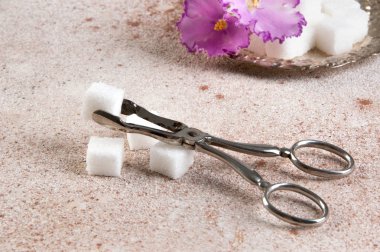 Küpleri beton zemin üzerine vintage şeker maşa ile vintage bir metal daire içinde beyaz şeker ve çiçek. Metin için yer kopyalayın