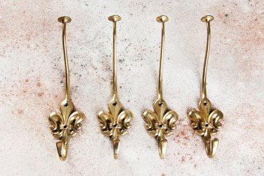 Dört vintage pirinç Fleur de Lis Duvar Askı beton zemin üzerine için kanca oluşturur. Metin için yer kopyalayın.