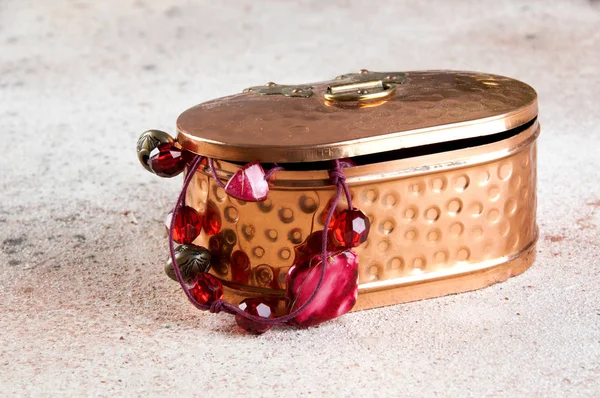 Vintage copper box with jewelry on concrete background. Copy space for text.