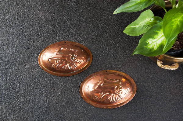 Vintage copper cookie molds and green plants on a black concrete background. Copy space for text