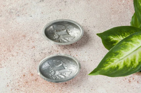 Inner side of vintage copper cookie molds and green plants on a concrete background. Copy space for text