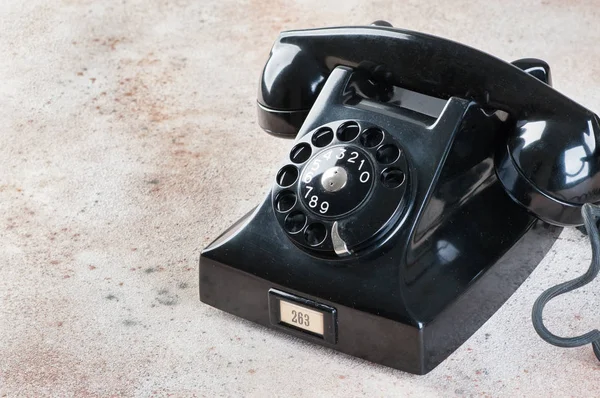 Antique black rotary phone on concrete background. Copy space for text.