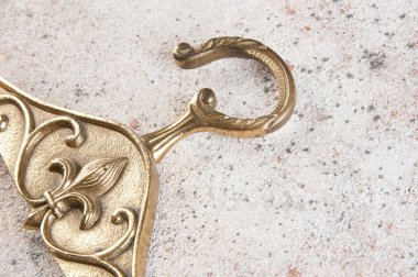 Antika pirinç elbise askısı Fleur de Lis beton zemin üzerine kapatın. Metin için yer kopyalayın.