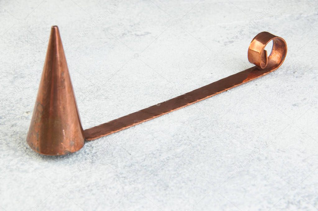 Antique copper candle snuffer on concrete background. Copy space for text.