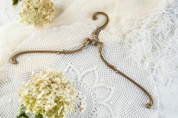 Vintage brass clothes hanger on crochet doily background. Copy space for text.