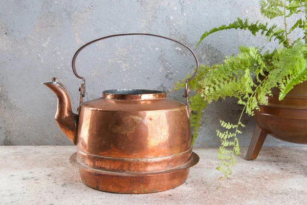 Antique copper kettle on concrete background.