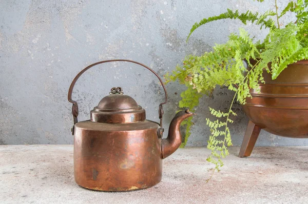 Antique copper kettle on concrete background.