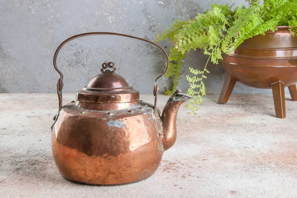 Antique copper kettle on concrete background.