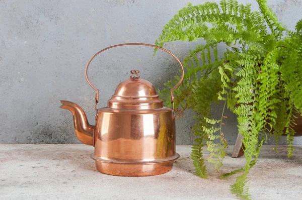 Antique copper kettle on concrete background.