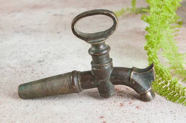 Antique bronze wine barrel crane on concrete background. — Stock Photo, Image