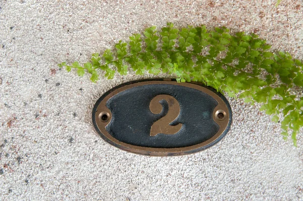 ประตูทองเหลืองหมายเลข 2 บนพื้นหลังคอนกรีต — ภาพถ่ายสต็อก