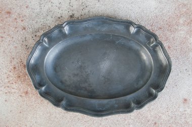 Antique pewter oval plate on concrete background.  clipart