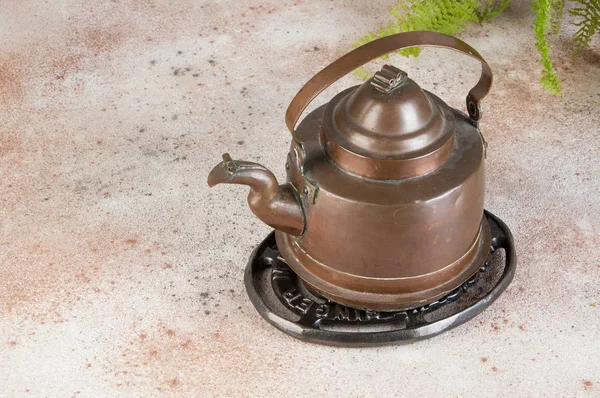 Vintage copper kettle on concrete background.