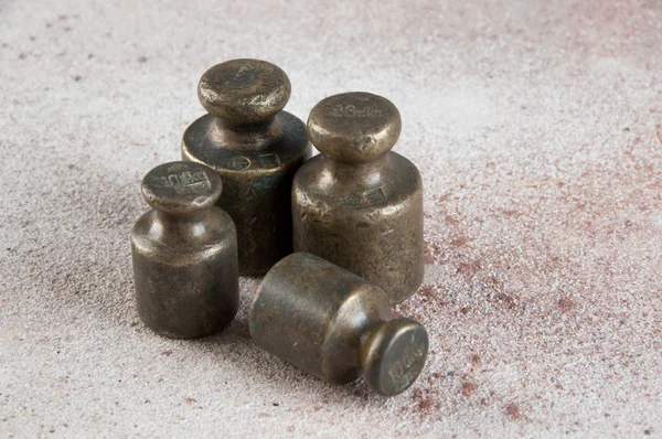 Antique bronze weights for scales on concrete background.