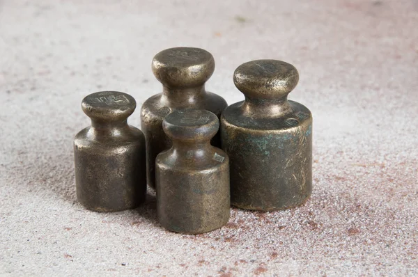 Antique bronze weights for scales on concrete background.