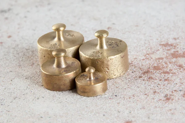 Pesos de bronce antiguos para escamas sobre fondo de hormigón . — Foto de Stock