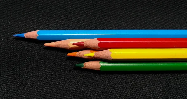 Isolated colored pencils on a black background with zenith light