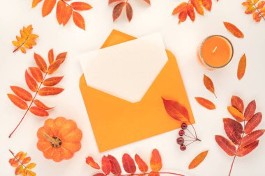 Yaratıcı sonbahar bembeyaz zemin üzerinde portakal ve kırmızı yapraklar, mum, balkabağı ve fotokopi alanı ile kaplanmış zarf