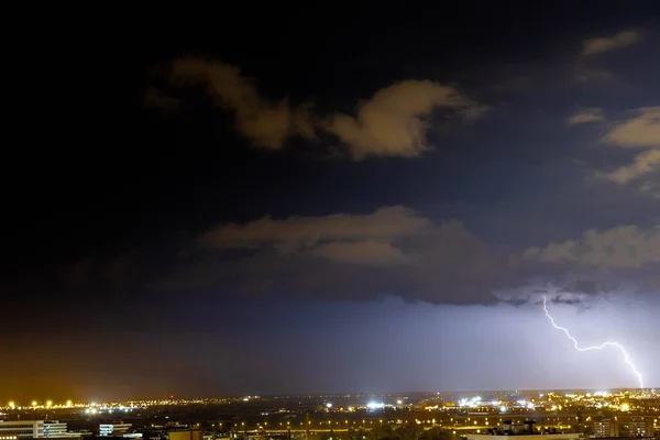 A blue sky with a thunders behind a city