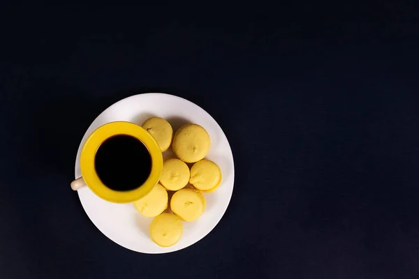 the coffee and yellow cookies on a black background, top view
