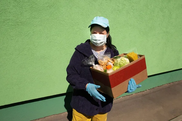 the women with a box of food, help and donation of food