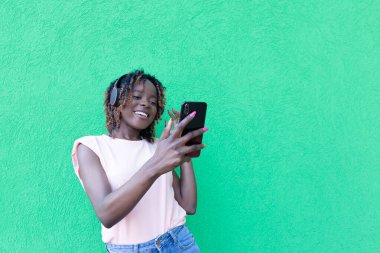 Kulaklıklı, telefonlu güzel Afrikalı Amerikalı.