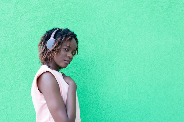The beautiful African American in headphones dancing, against a green background